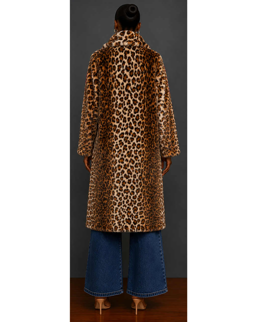Person wearing a leopard print coat and blue jeans against a plain background