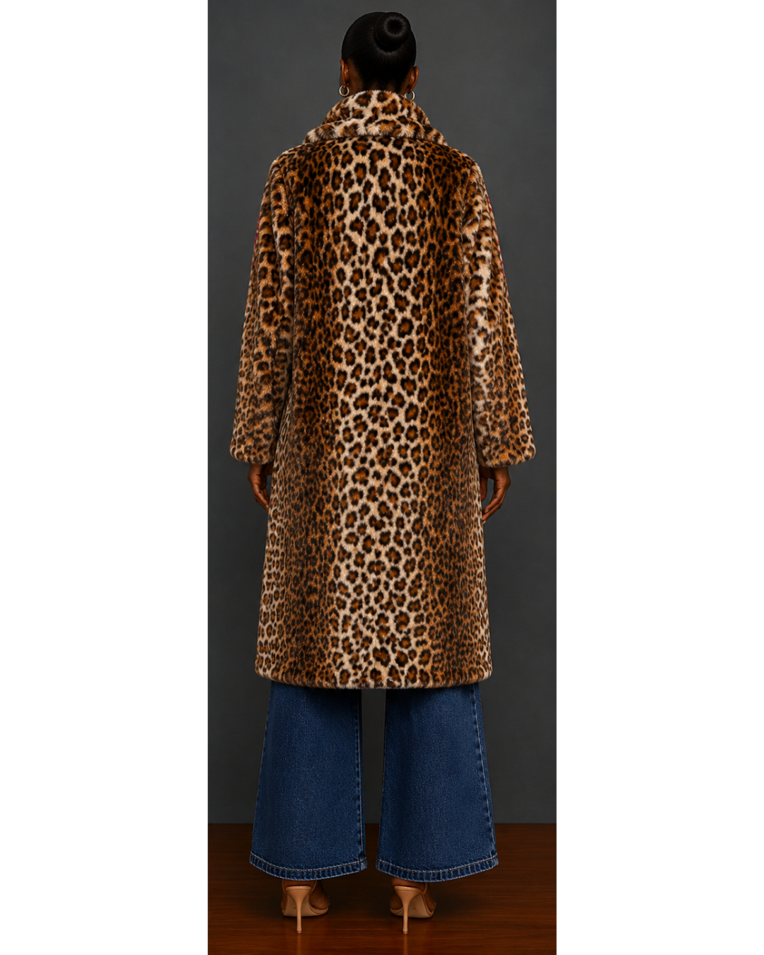 Person wearing a leopard print coat and blue jeans against a plain background