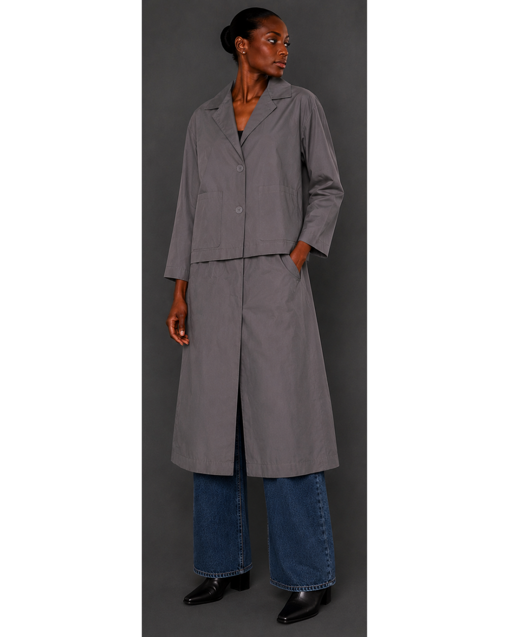 Woman wearing a long gray coat over a blue dress against a gray background
