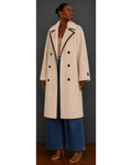 Front view of woman wearing a beige coat with black buttons against a gray background