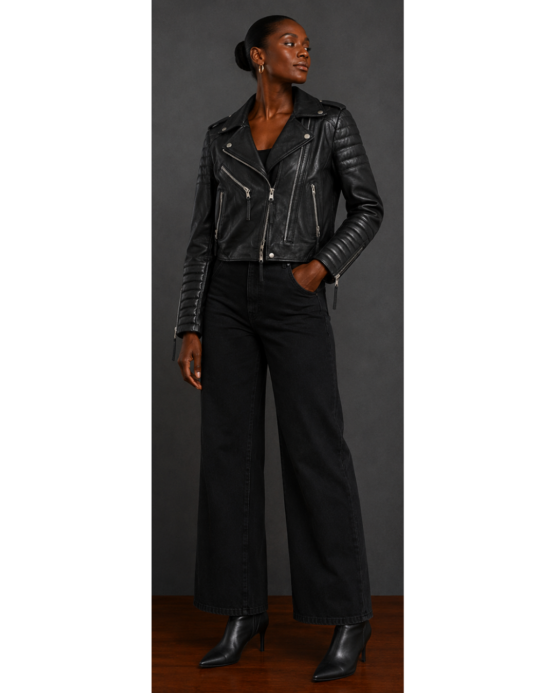 Person wearing a black leather jacket and pants against a gray background