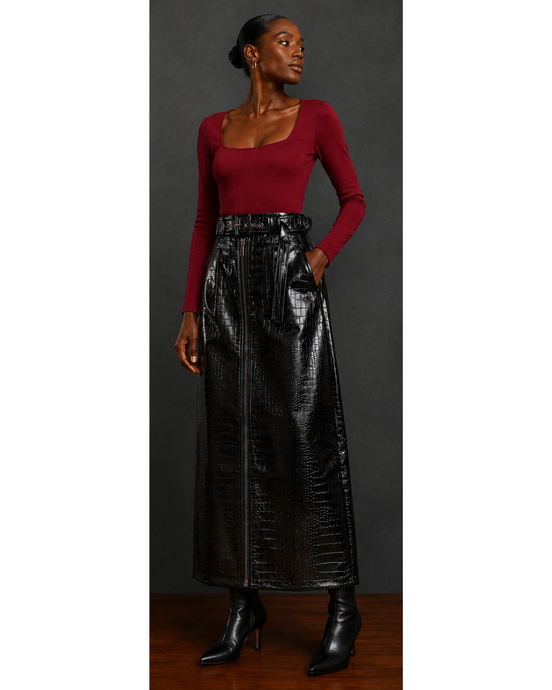 Front view of a woman wearing a red top and black leather skirt against a dark background
