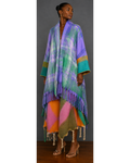 Front view of woman wearing a colorful plaid poncho with fringe details on a gray background