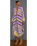 Front view of a woman wearing a colorful patterned blanket wrap coat with fringe against a gray background