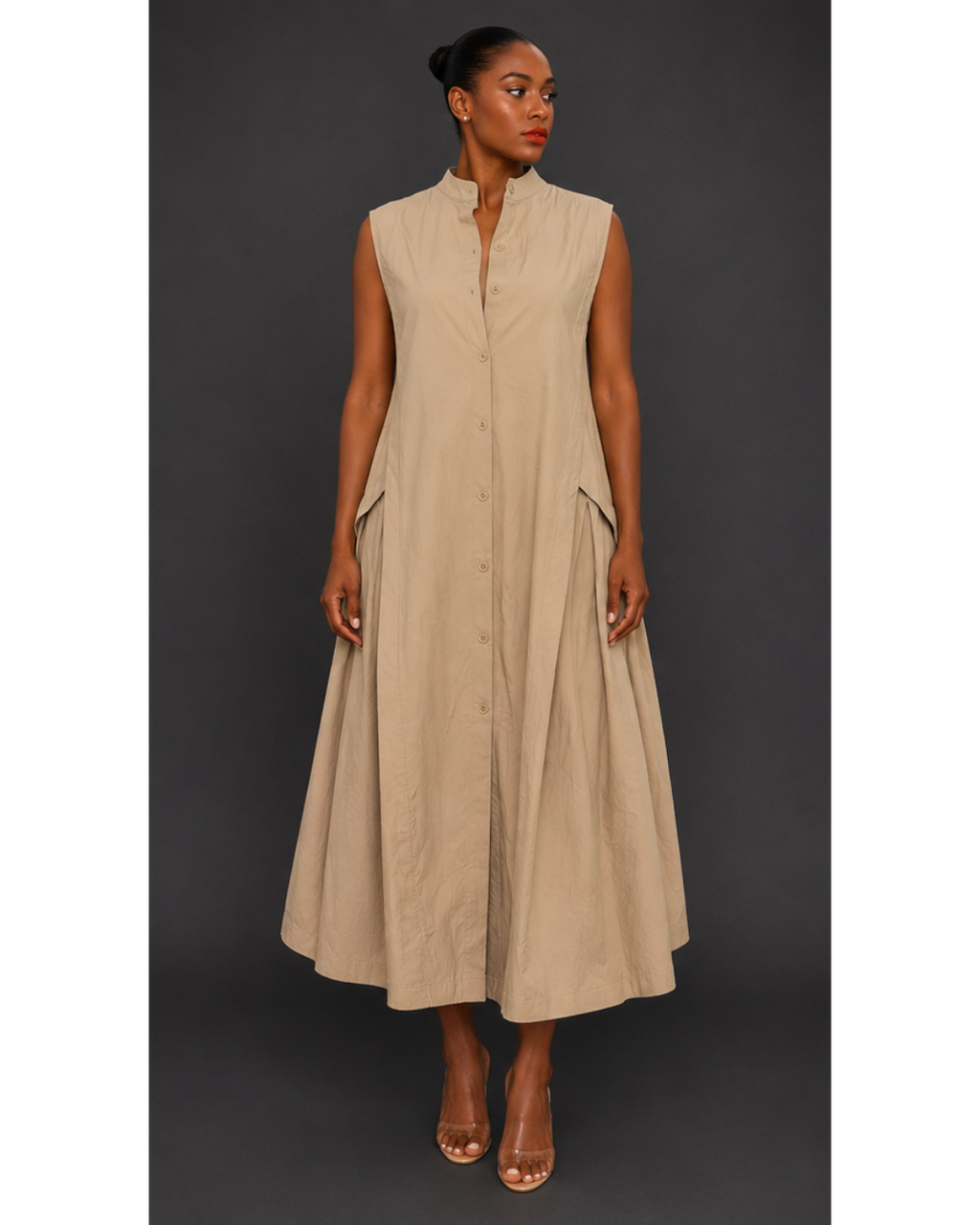 Front view of a woman wearing a beige sleeveless pleated maxi dress against a dark background