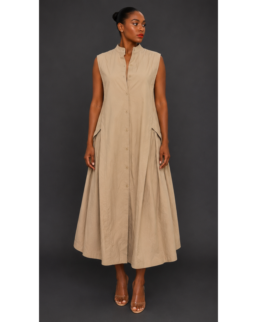 Front view of a woman wearing a beige sleeveless pleated maxi dress against a dark background