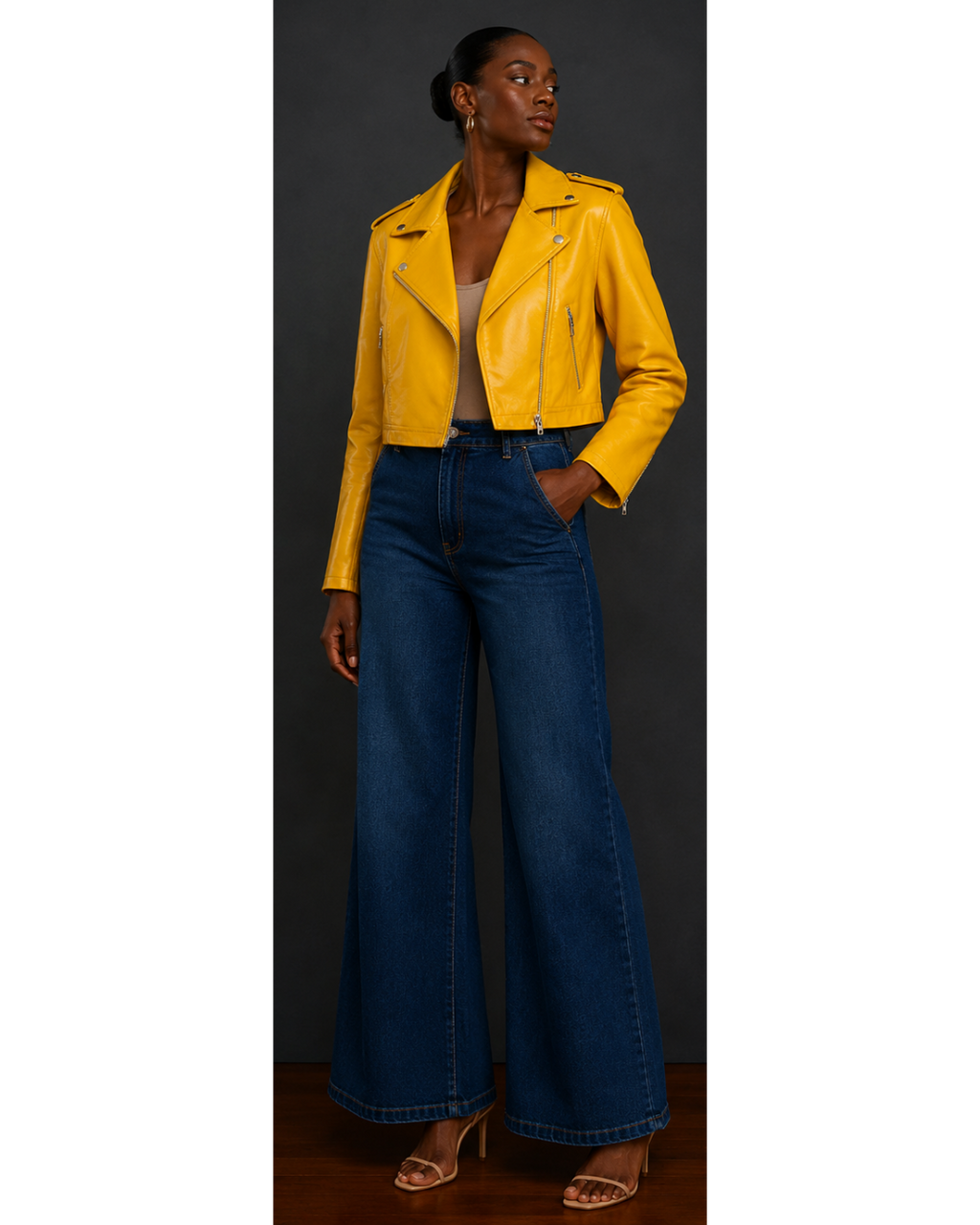 Front view of woman wearing a yellow leather jacket and blue jeans on a plain background