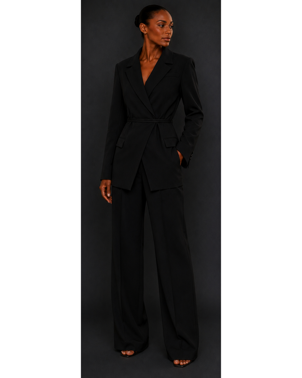 Woman wearing a black blazer and black trousers against a dark background