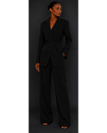 Woman wearing a black blazer and black trousers against a dark background