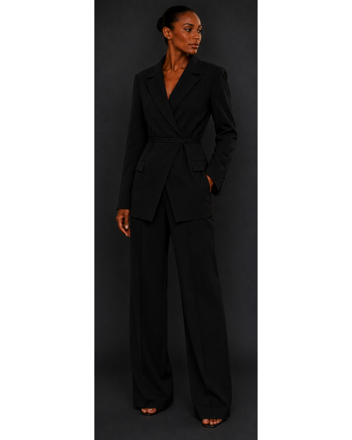 Woman wearing a black blazer and black trousers against a dark background
