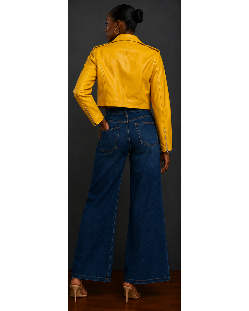 Back view of woman wearing a yellow leather jacket and blue jeans on a plain background