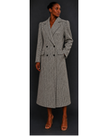 Woman wearing a long, houndstooth coat against a dark background