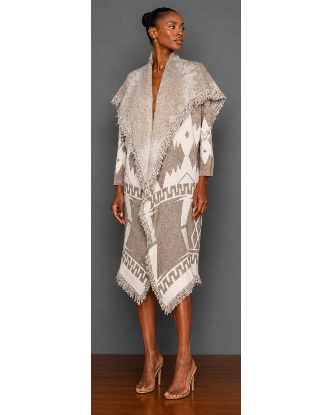 Woman wearing a neutral colored patterned blanket wrap coat with a plain charcoal gray background