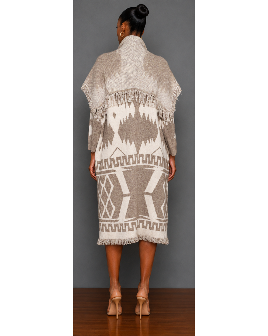 Woman wearing a neutral colored patterned blanket wrap coat with a plain charcoal gray background