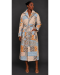 Front view of a woman wearing a long, patterned quilted blanket coat against a dark background
