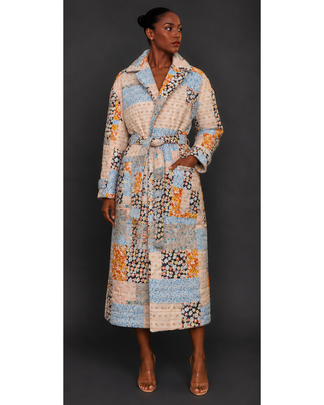 Front view of a woman wearing a long, patterned quilted blanket coat against a dark background