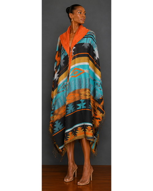 Front view of woman wearing a teal, orange, brown, gold, and black patterned blanket wrap coat with orange hood