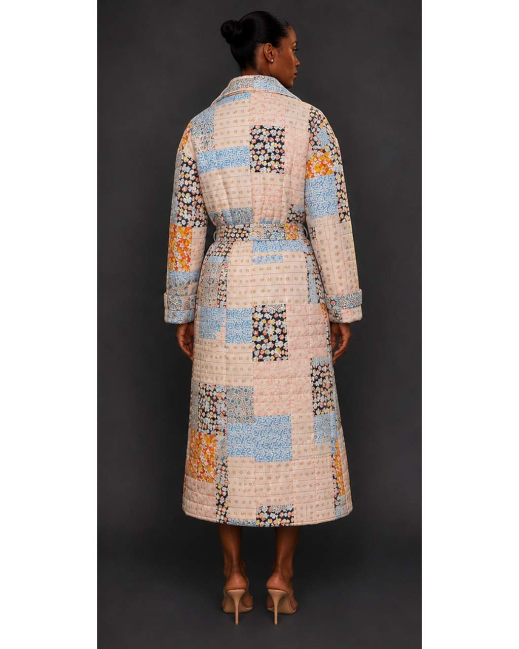 Back view of a woman wearing a long, patterned quilted blanket coat against a dark background