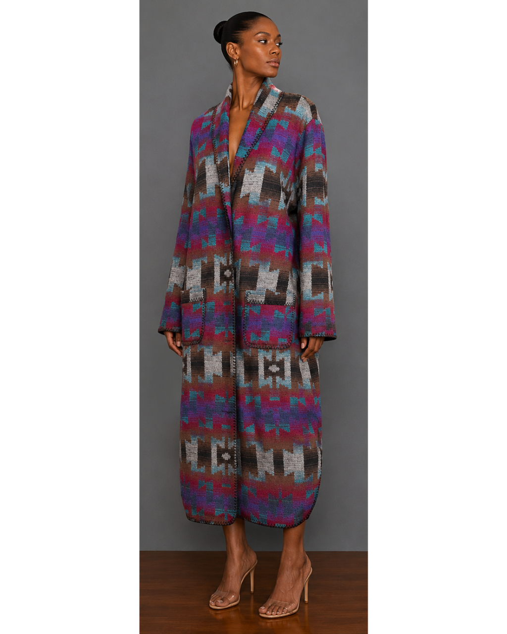 Front view of woman wearing a teal, red, brown, brown, gray, purple, and black patterned blanket wrap coat with collar and front patch pockets