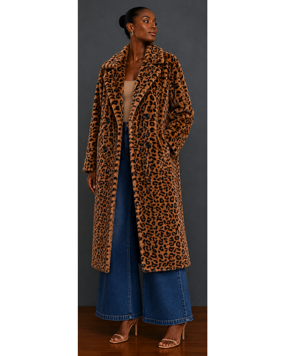 Front view of woman wearing a leopard print faux fur coat and blue jeans against a gray background