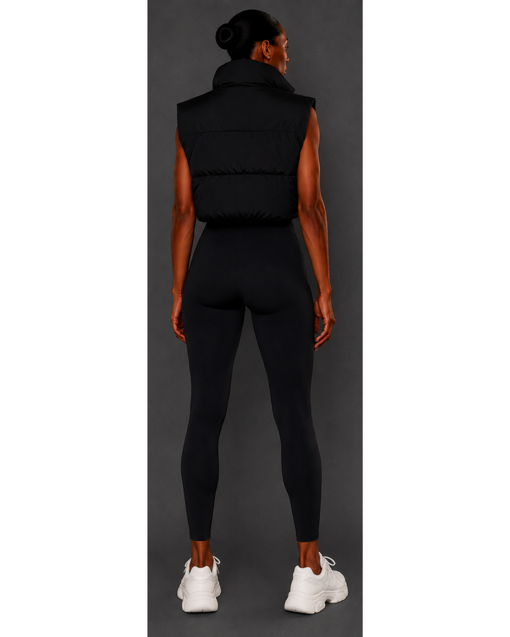 Person wearing a black puffer vest and leggings set on a gray background