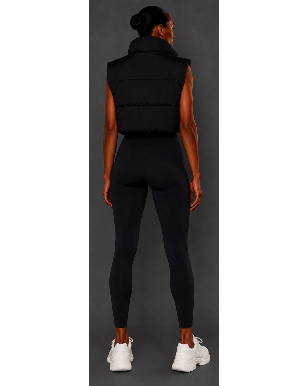 Person wearing a black puffer vest and leggings set on a gray background