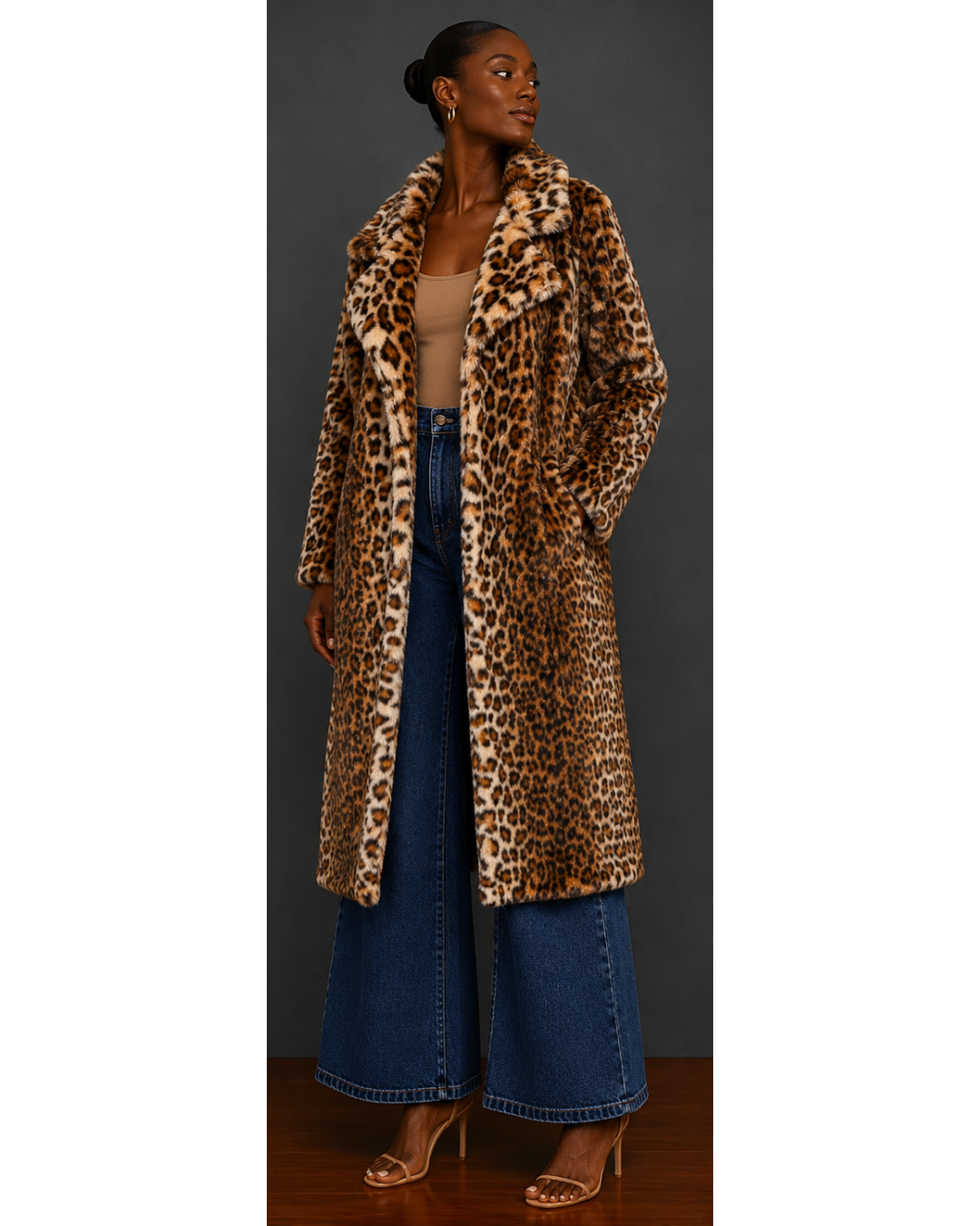 Woman wearing a leopard print coat and blue jeans against a neutral background
